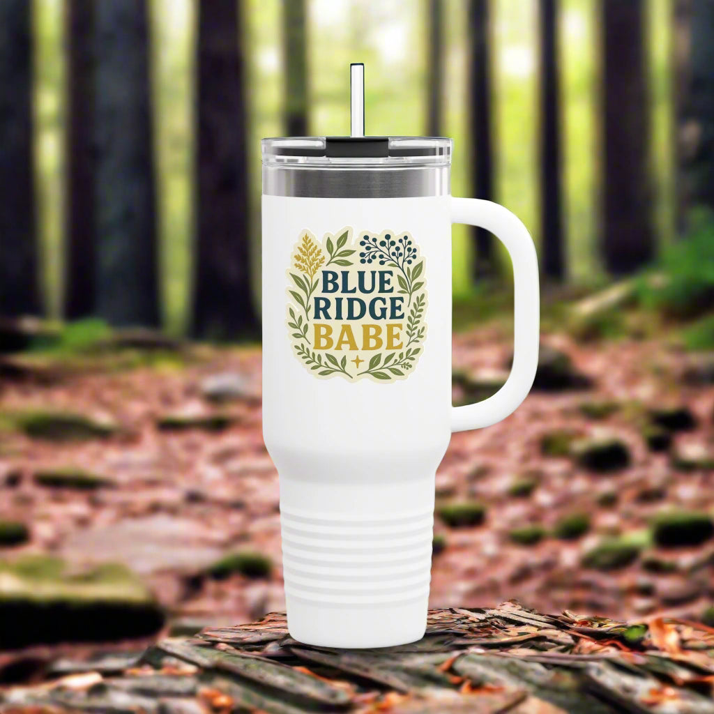 White tumbler with 'Blue Ridge Babe' design in a forest setting
