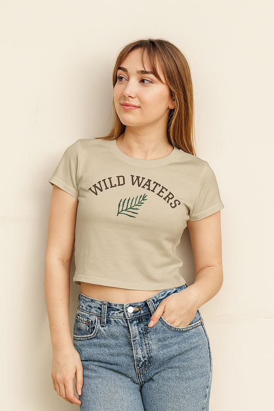 Woman wearing a beige t-shirt with 'Wild Waters' text and a leaf graphic against a plain background