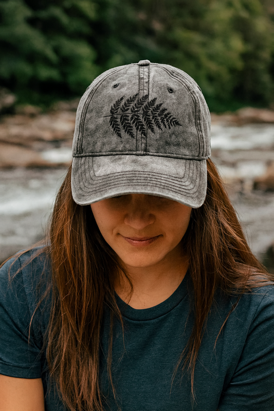Person wearing a gray cap with a fern design outdoors