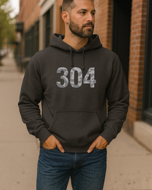 Man wearing a black hoodie with '304' printed on it, standing on a sidewalk.