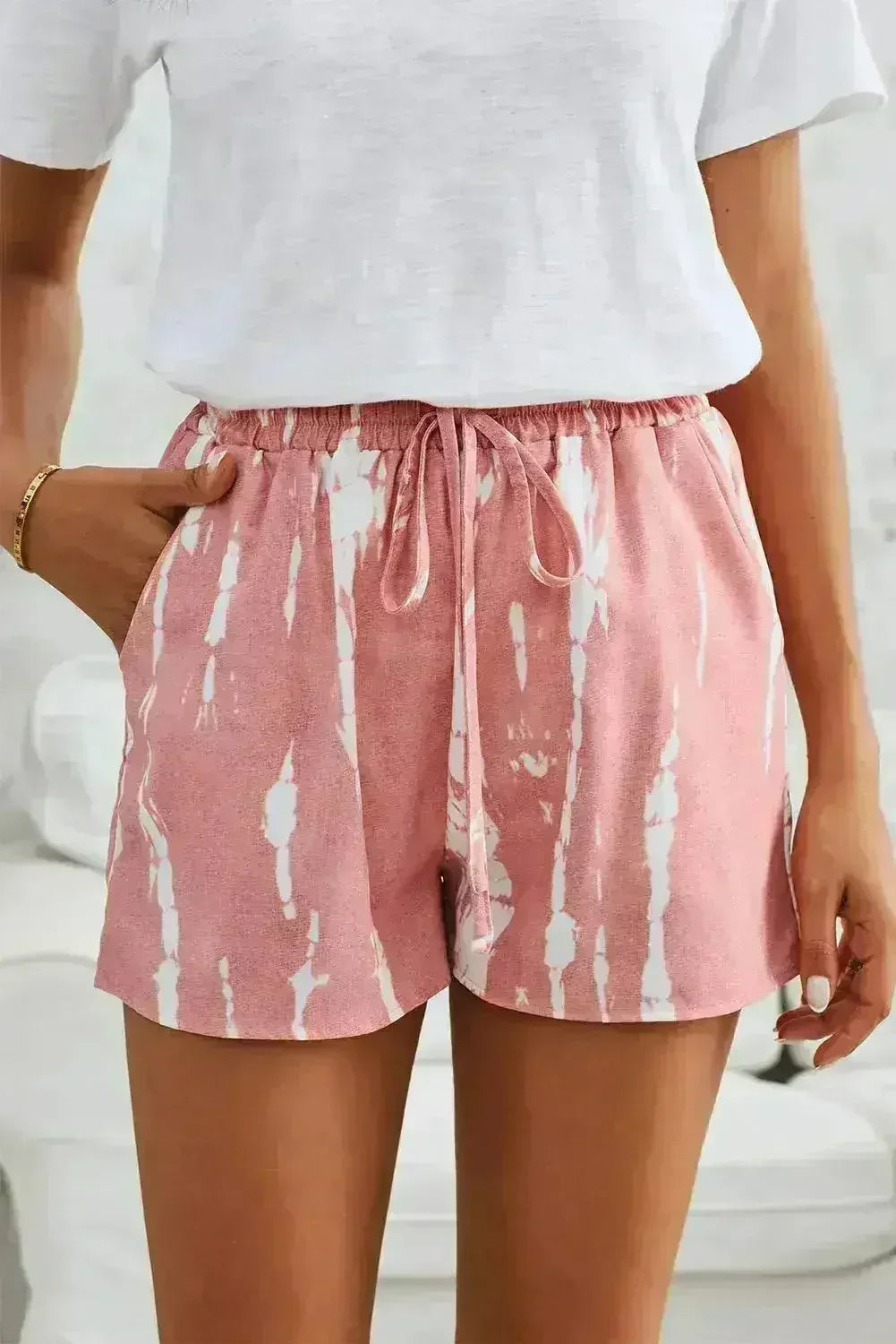Person wearing pink tie-dye shorts with a white top on a blurred background