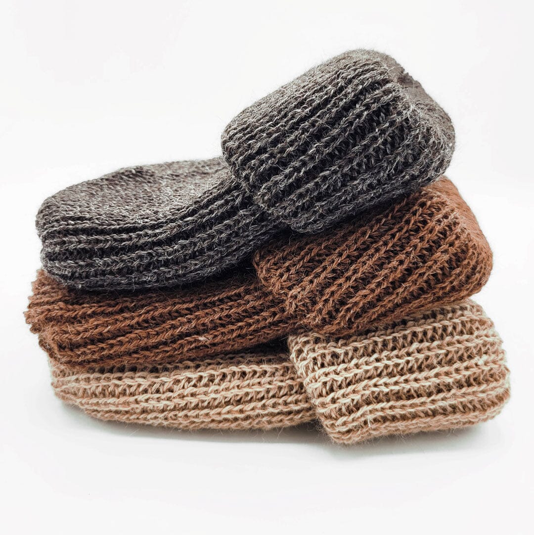 Stack of brown and gray knitted slippers on a white background